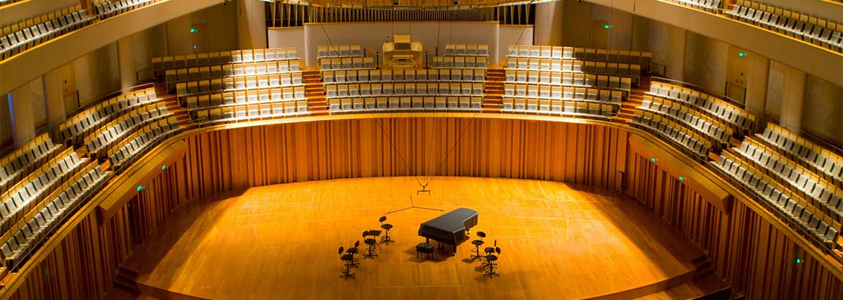 A grand piano and chairs on the stage of a concert hall