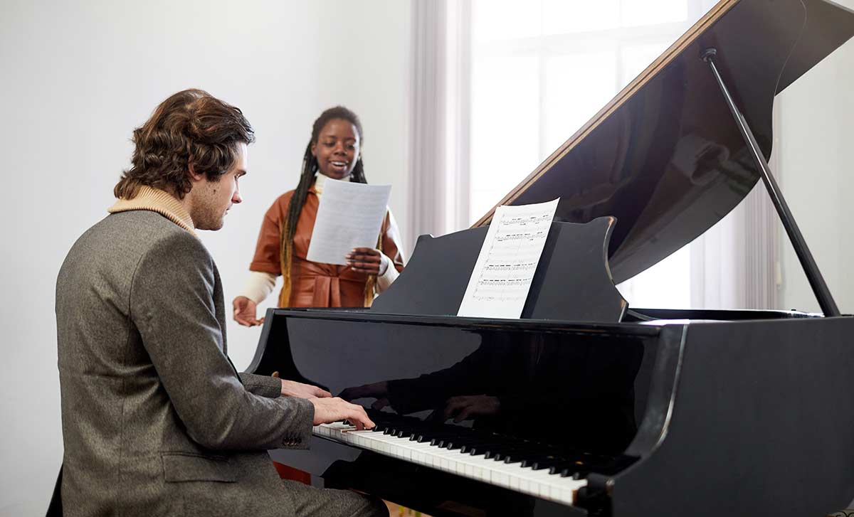 A man playing piano with a female singer
