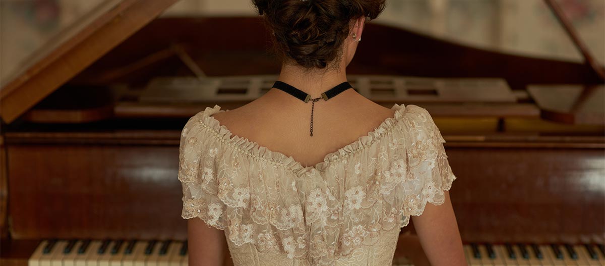 Back view of classic lady wearing lace dress playing grand piano