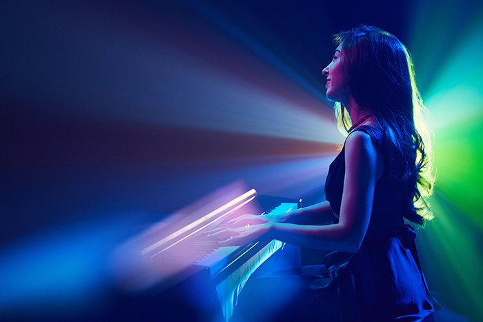 Beautiful pianist plays with different spot light colors background feat