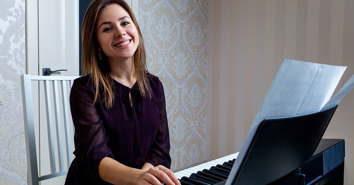 Beautiful smiling lady with hand on the piano