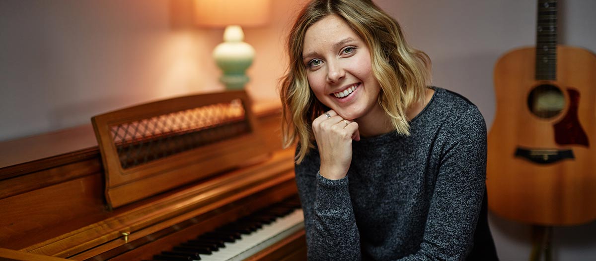 Beautiful woman smiling sitting with piano and guitar background