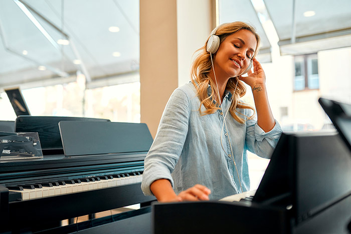 Beautiful woman wearing headphones listening to music while playing the piano feat