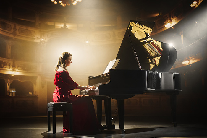 Beautiful women playing the grand piano on stage with spot light