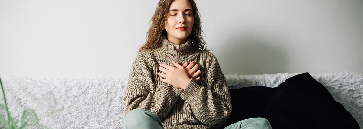 Calm woman sitting with eyes closed and hands on chest