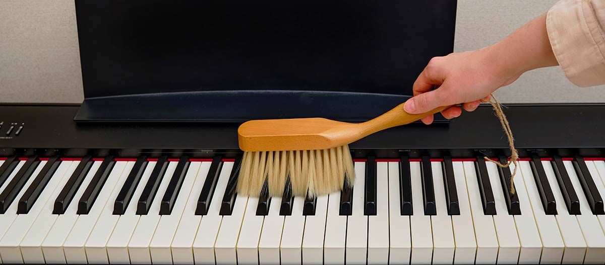 Hand cleaning piano keys with a brush