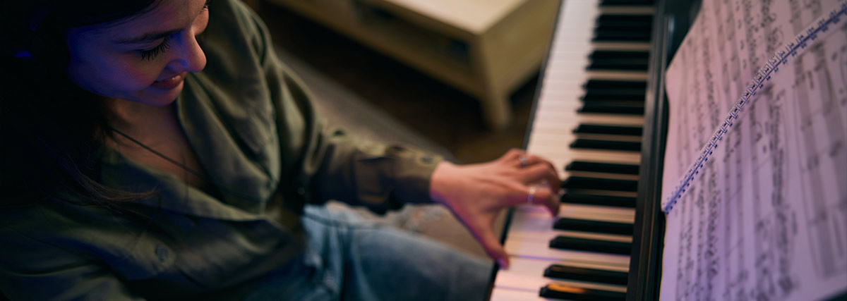 Happy woman playing piano with sheet music