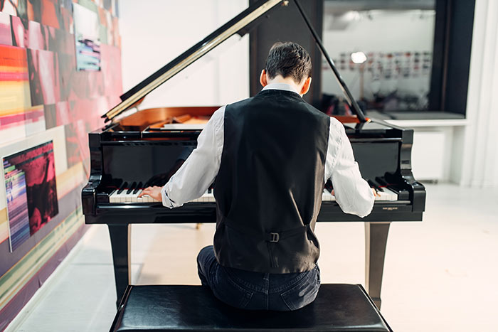 Male pianist playing a composition on grand piano