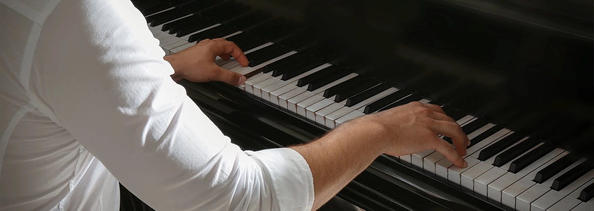 Man in a white long sleeve playing piano