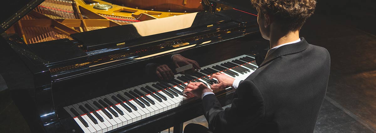 Man in suit playing grand piano