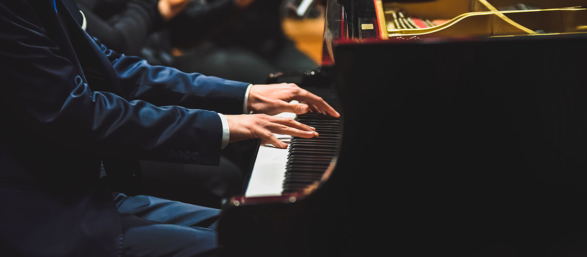 Man in suit playing grand piano