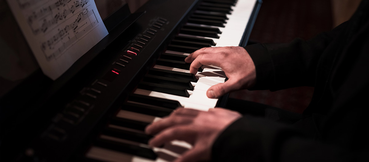 Man in suit playing piano with sheet music