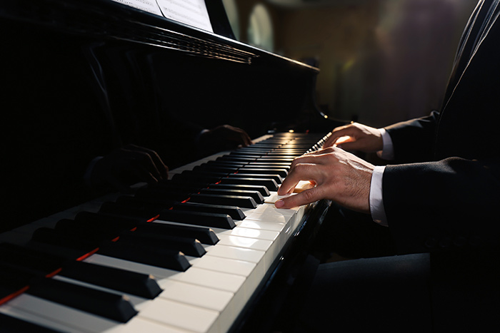 Man in suit playing piano feat
