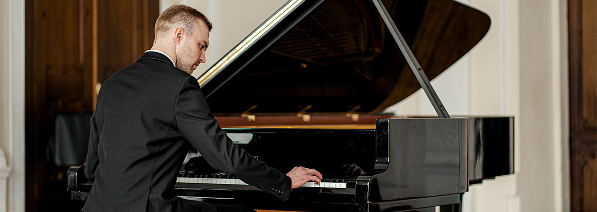 Man in suit playing the grand piano
