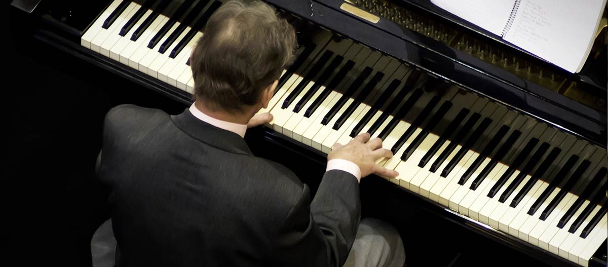 Man in suit playing the grand piano