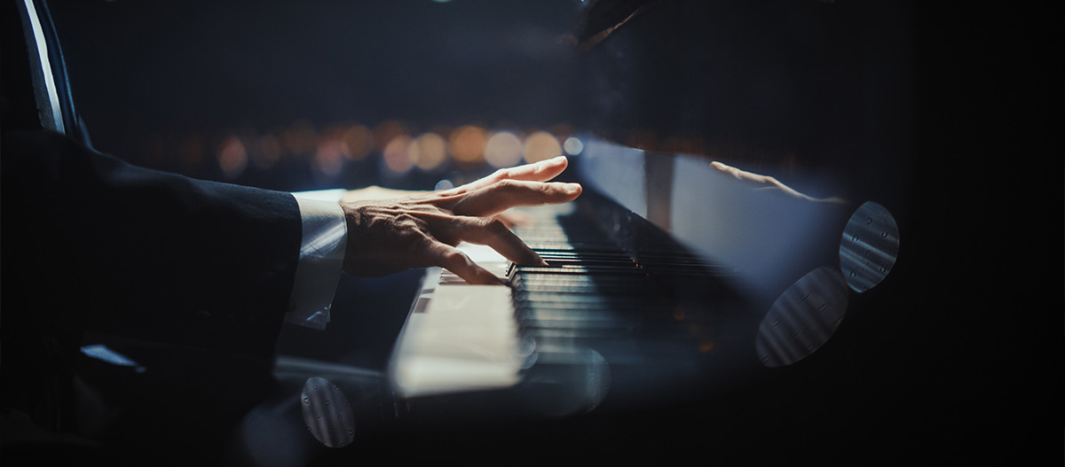 Man in suit with hands on the piano keyboard