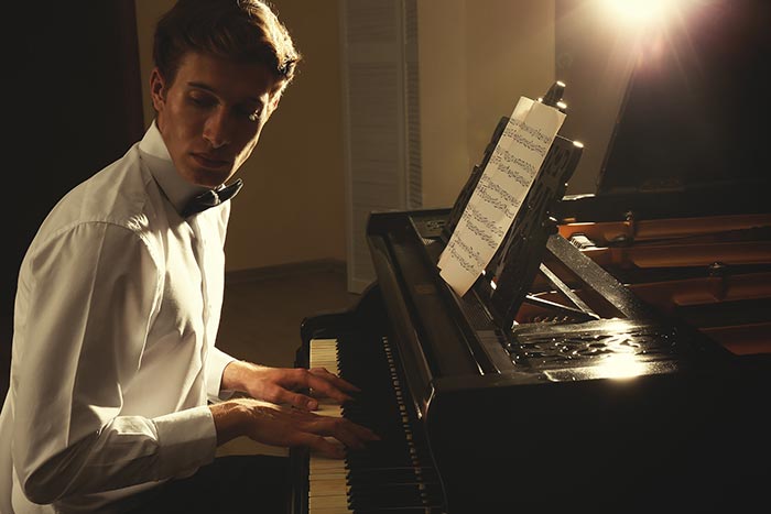 man looking away while playing the piano feat