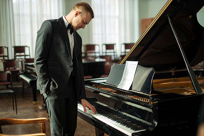 man standing in front of the piano feat