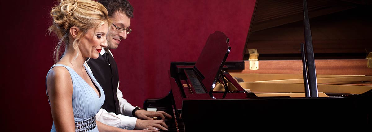 middle aged man and woman playing the piano