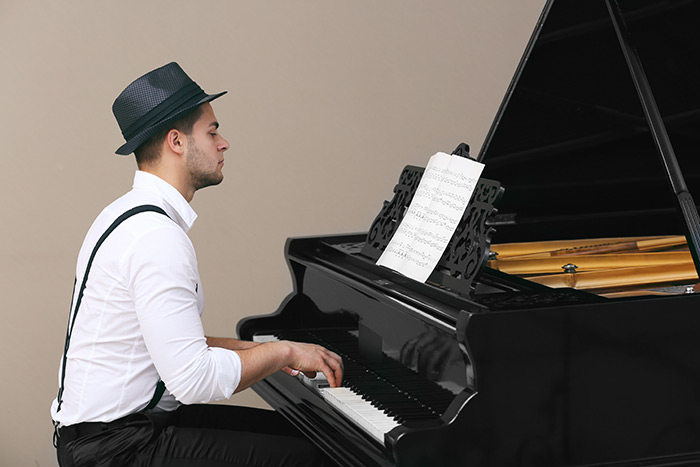 Pianist with a hat playing on a grand piano