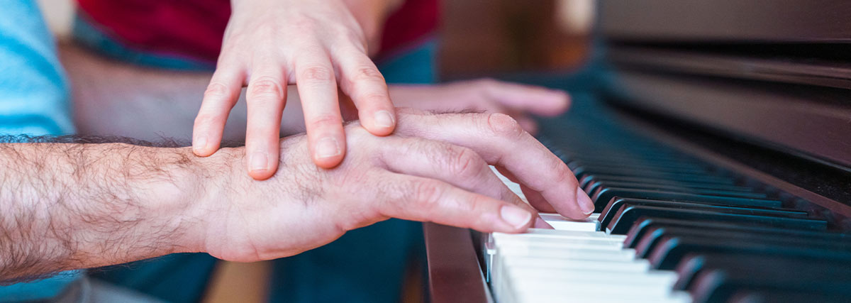 Teacher teaching student of proper hand placement on the piano