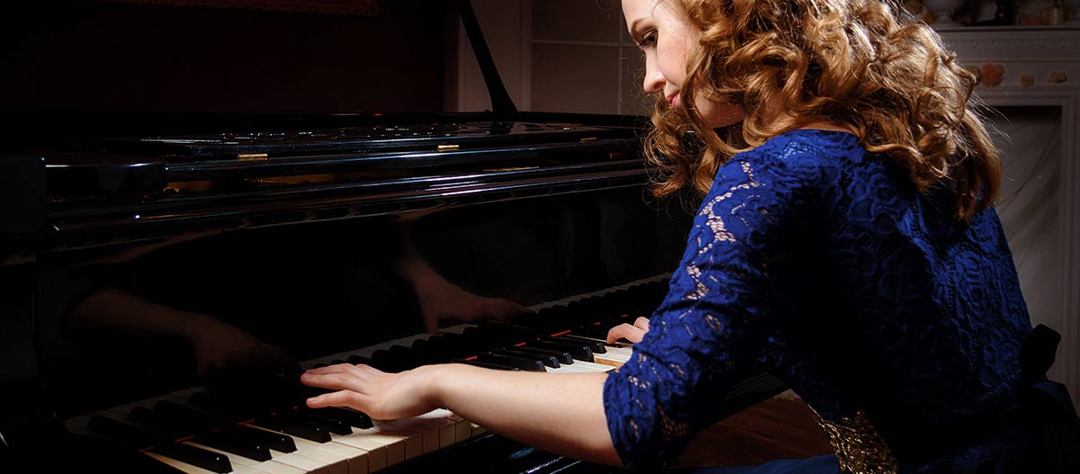 Woman in blue dress playing piano