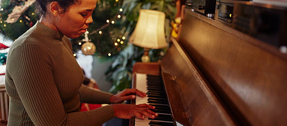 Woman playing piano with Christmas tree in the background