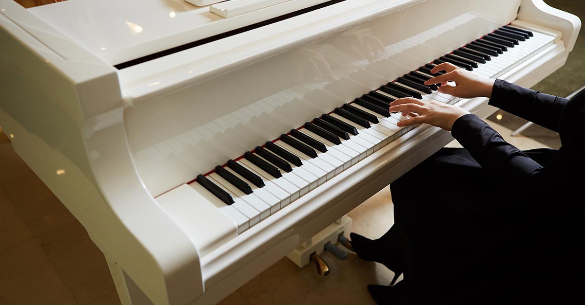 Woman playing white grand piano