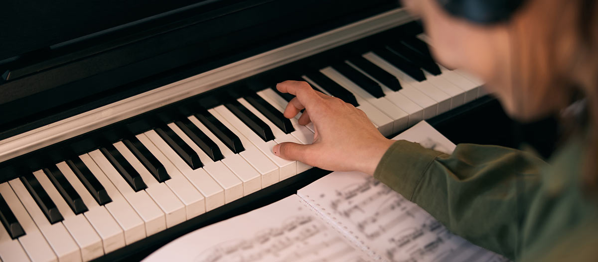 Woman reading sheet music while playing piano