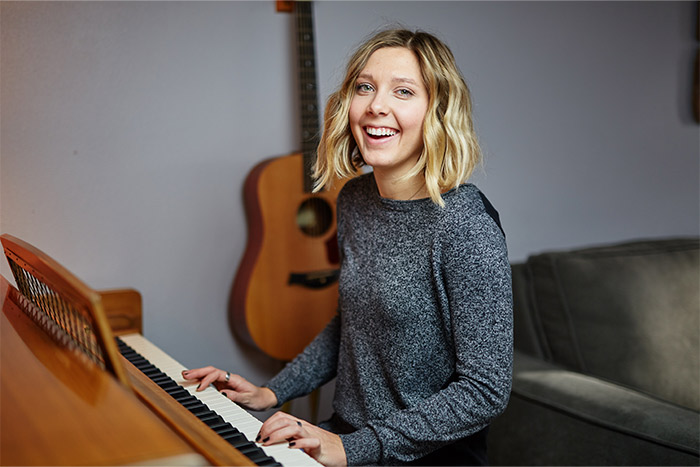 Woman smiling playing piano feat